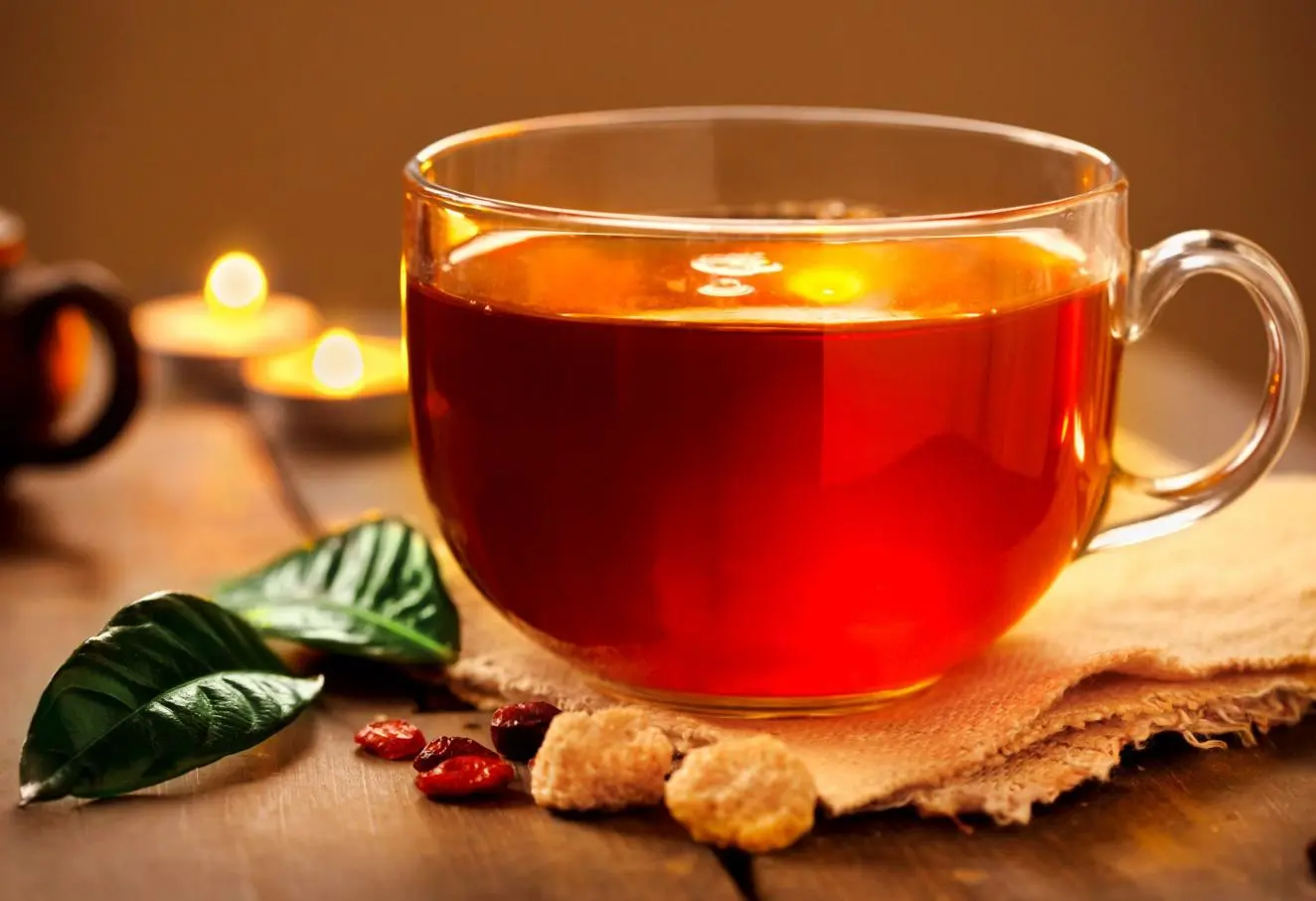 چای سبز در ظرف شیشه‌ای با برگ‌های تازه