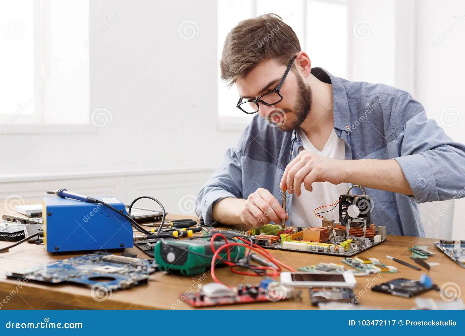 تعمیرکار در حال جدا کردن مادربرد کامپیوتر با پیچ‌گوشتی و ابزارهای تخصصی