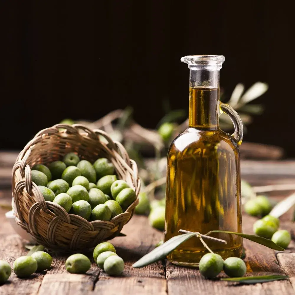 بوتلی از روغن زیتون فراورده نشده با برچسب و برگه‌های زیتون تازه
