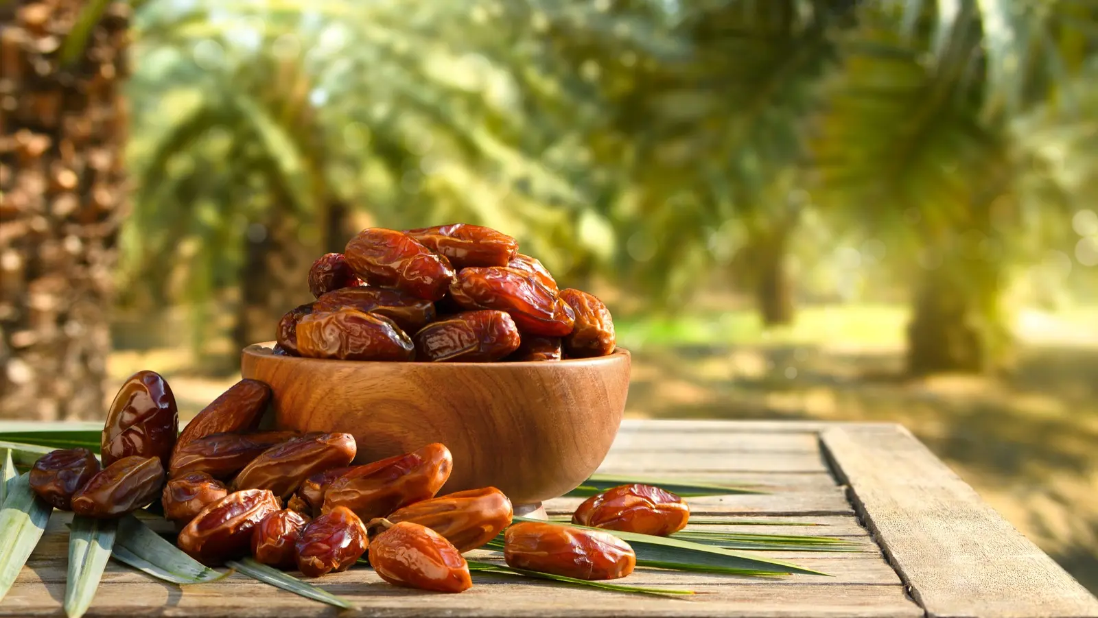 خرماهای مختلف در یک سبد چوبی و یک ظرف شیشهای